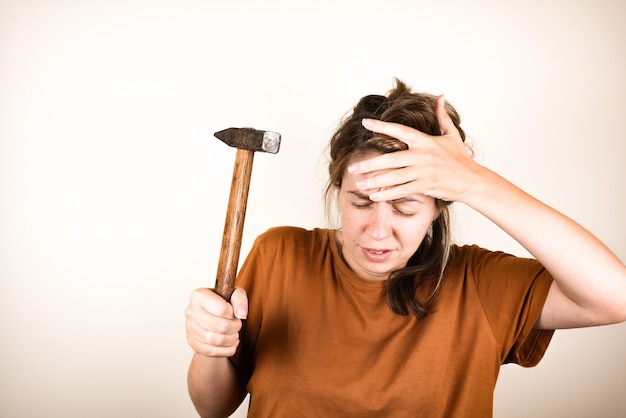 Angry woman holding her forehead and hammer