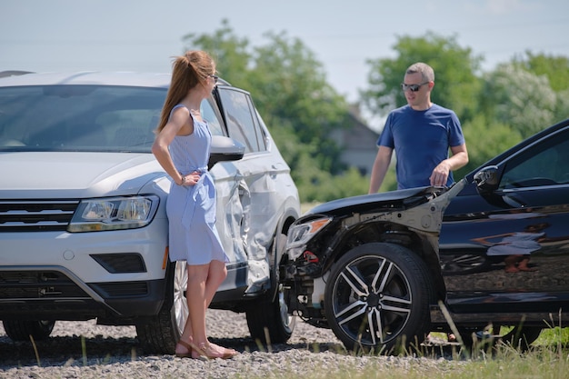 Angry woman and man drivers of heavily damaged vehicles arguing who is guilty in car crash accident on street side Road safety and insurance concept