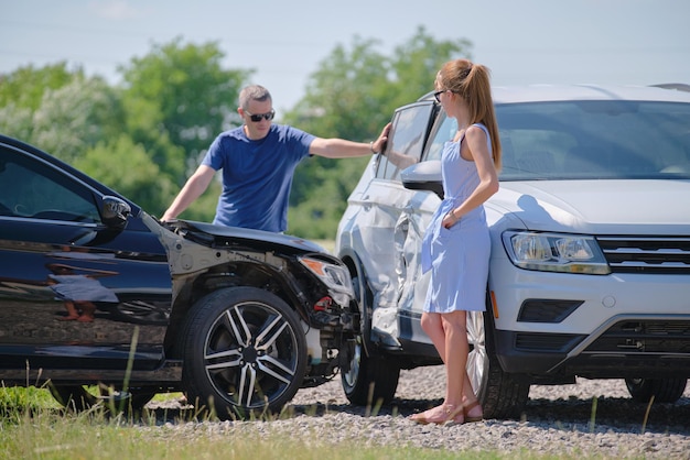 Angry woman and man drivers of heavily damaged vehicles arguing
who is guilty in car crash accident on street side road safety and
insurance concept