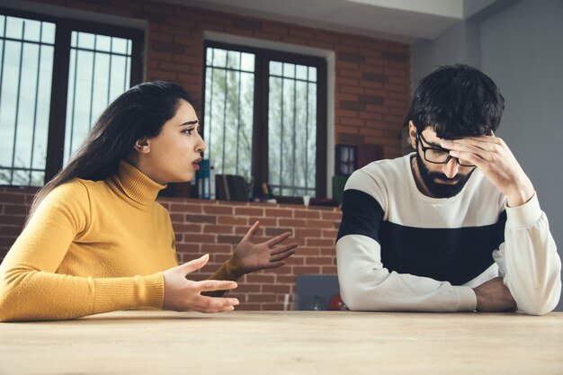 テーブルの上の怒っている女性と悲しい男