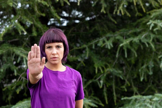 Angry woman with in purple showing the hand palm saying STOP