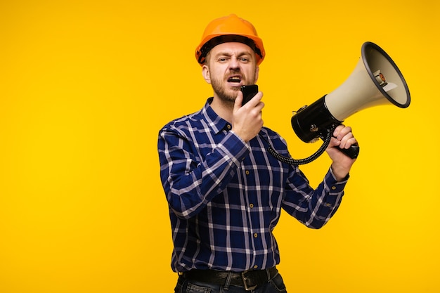 Angry worker man in orange helmet with a megaphone on yellow - Image