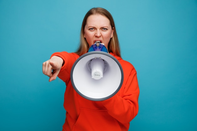 Angry young blonde woman pointing at side talking by speaker 