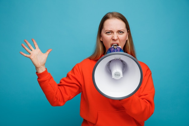 Photo angry young blonde woman showing empty hand talking by speaker