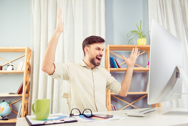 Angry young businessman working in office and screaming