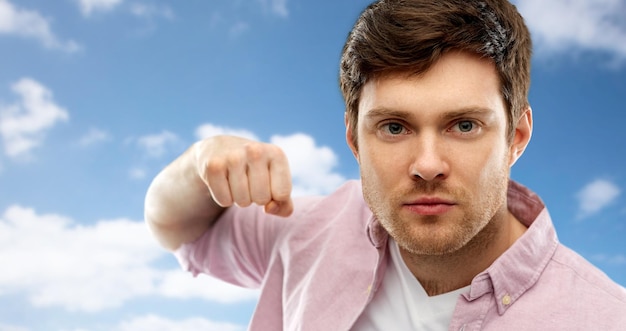 Photo angry young man ready for fist punch over sky