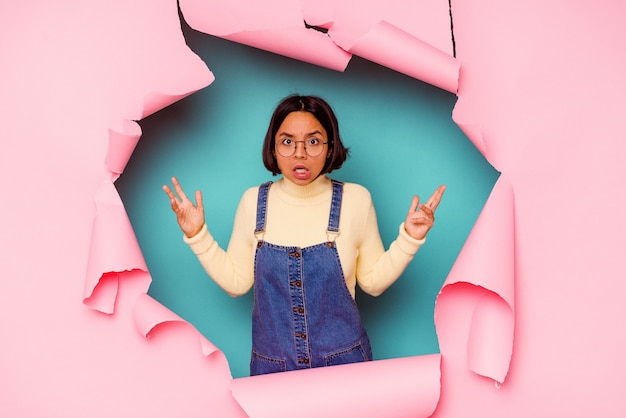 Angry young woman behind a broken wall