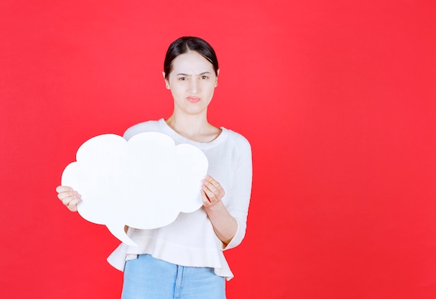 Angry young woman holding speech bubble with a cloud shape