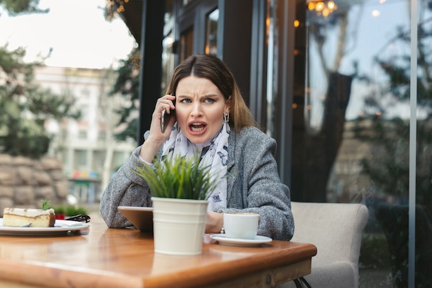 Angry young woman solving business problems shouting during phone conversation