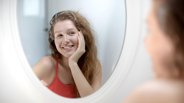 Angstige jonge vrouw kijkt in de spiegel bezorgd over rimpel of acne op ongezonde huid overstuur ongelukkige millennial vrouw onderzoekt knijp puistje op gezicht in de slaapkamer cosmetologie huidverzorging concept