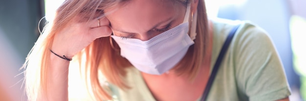 Angstige trieste vrouw met medisch beschermend masker zit aan tafel