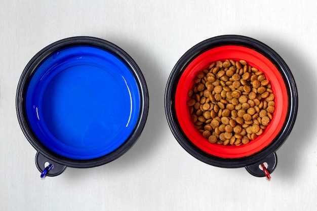 Animal food in a red pot and water in a blue pot on the floor