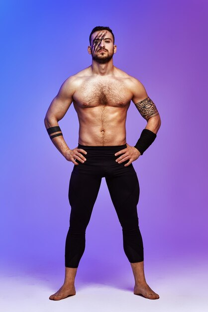 Photo animal instinct fitness instructor sportsman showing his incredible flexibility with an animal flow move in studio against a pink blue gradient background