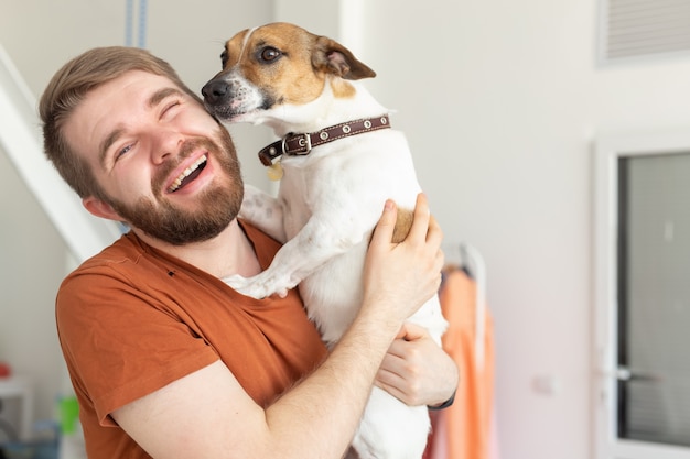 動物、ペット、人々のコンセプト-ジャックラッセルテリアとカジュアルなマスタードTシャツを着た笑顔の男。