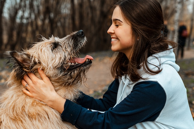 Animal training. a volunteer girl walks with a dog from an
animal shelter. girl with a dog in the autumn park. walk with the
dog. caring for the animals.