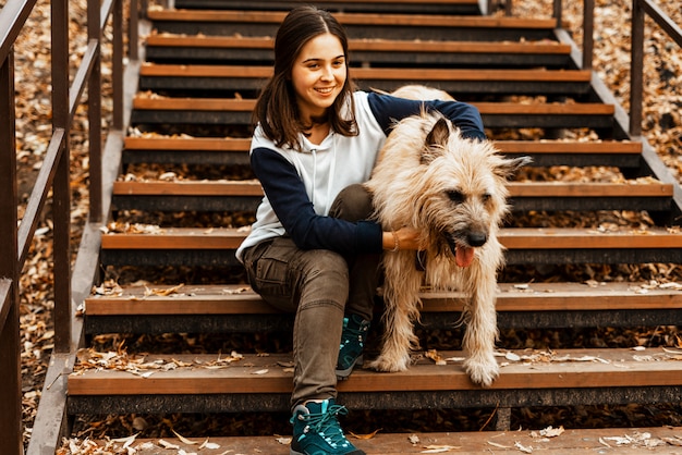 Animal training. A volunteer girl walks with a dog from an animal shelter. Girl with a dog in the autumn park. Walk with the dog. Caring for the animals.