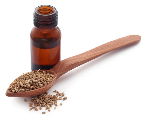 Anise seeds with essential oil in a jar over white background