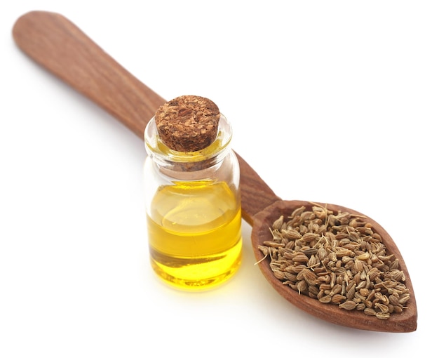 Anise seeds with essential oil in a jar over white background