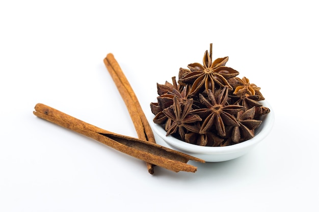 Anise spice on a wooden spoon on a white wall.