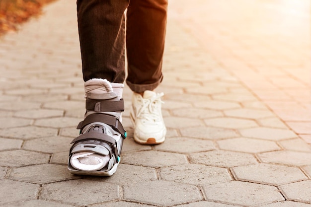 Photo ankle brace, orthopedic ancle support shoes. injuried woman with splint, walker boot, orthosis