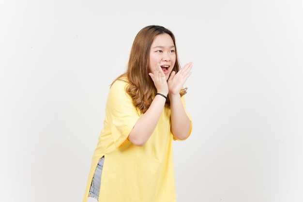 흰색으로 격리된 노란색 티셔츠를 입은 아름다운 아시아 여성의 입을 통해 손으로 발표