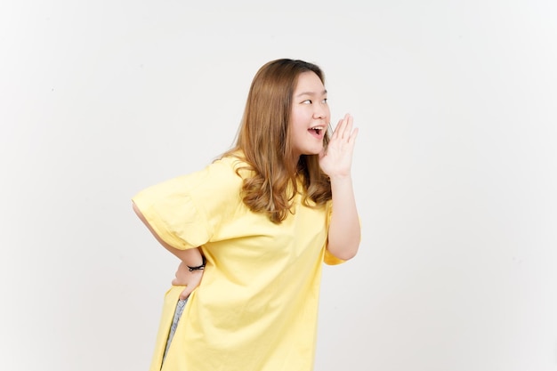 Announcement with hands over mouth of Beautiful Asian Woman wearing yellow TShirt Isolated On White