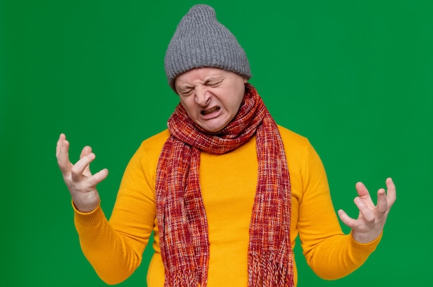 Annoyed adult slavic man with winter hat and scarf around his neck squeezing his fingers 