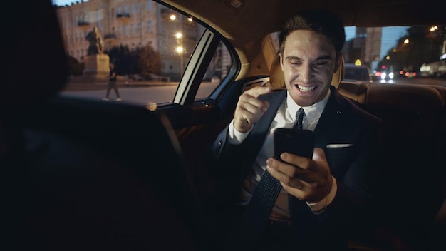 Foto uomo d'affari infastidito che impreca sulla chat video su smartphone in macchina scura