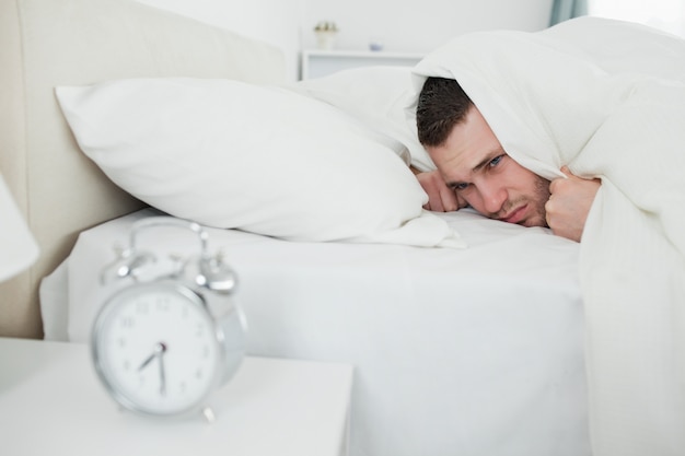 Annoyed man being awakened by an alarm clock