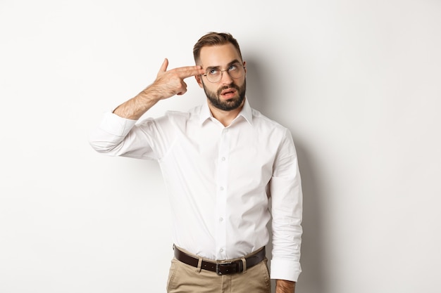 Annoyed man making shooting in head and roll eyes, standing distressed over white background