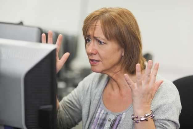 Annoyed mature woman working on computer