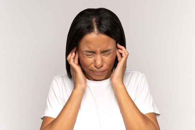Раздраженная напряженная женская крышка уха избегает шумных звуков страдает от головной боли, беспокойства или психических проблем
