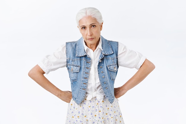 Annoyed tired and fed up seriouslooking granny cant deal with nasty child hold hands on waist look with scorn and disappointment losing patience and temper stand white background frustrated