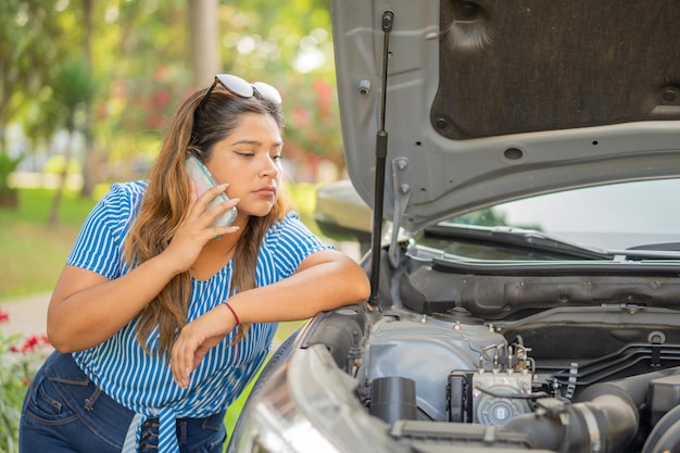 Photo annoyed woman calling emergency services because her vehicle broke down in the street