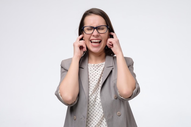 Annoyed woman plugs fingers in ears not listening to loud noise