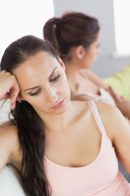 Annoyed woman sitting next to her friend on a couch