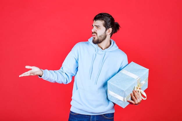 Annoyed young man holding his present and looking right side