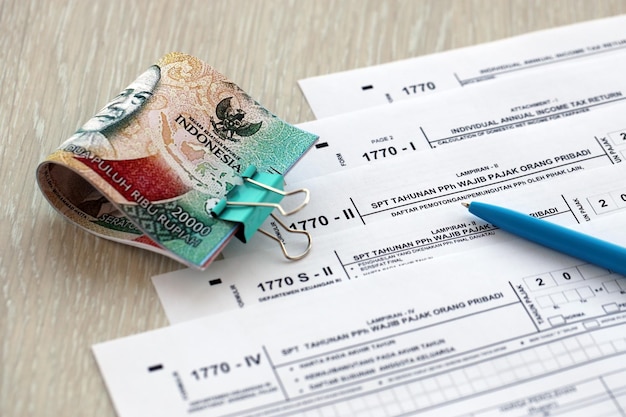 Photo annual individual income tax return forms with pen and indonesian rupiah bills