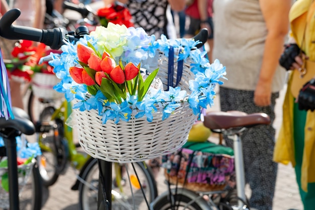 Parata annuale della bici delle donne primo piano un cesto bianco con fiori blu e rossi su una bicicletta