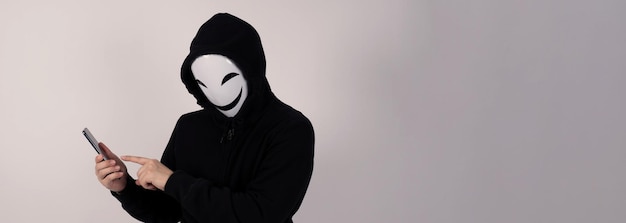 Anonieme hacker en gezichtsmasker met smartphone in de hand