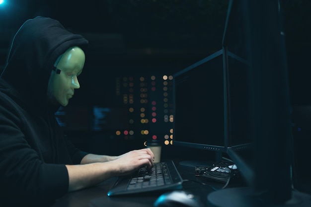 Anonieme hacker met masker op gezicht verbreekt de toegang om informatie te stelen en computers te infecteren