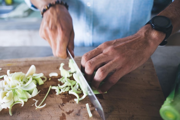 Anonieme persoon die greens op een houten bord snijdt