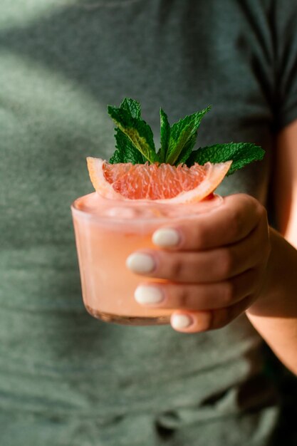 Anonieme persoon met een koud drankje gemaakt met grapefruit en munt