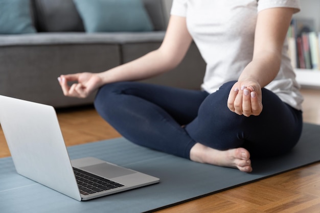 Anonieme vrouw die voor laptop mediteert Virtueel meditatieklasconcept