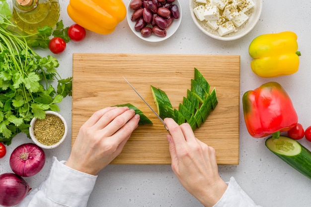 Anonieme vrouwelijke snijingrediënten voor Griekse dorpshoriatiki salade voedsel achtergrond plat leggen