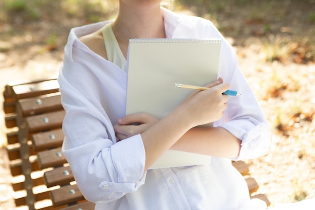 Ragazza anonima che prende appunti o disegna il libro di carta bianco