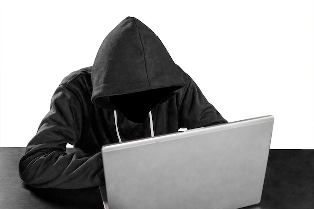 Anonymous hacker working on laptop on white background