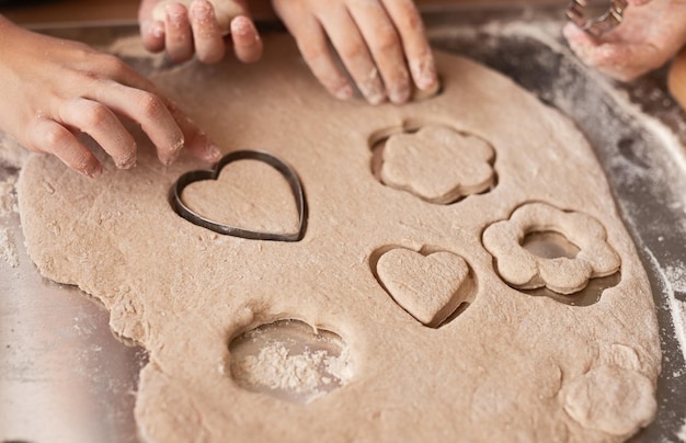 Anonymous kids cutting cookies from dough