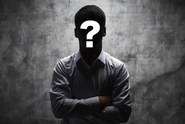 Anonymous man in a business shirt with question mark on his face on dark background