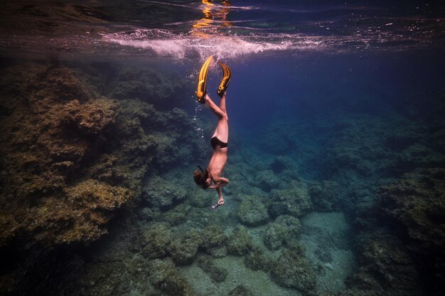 Anonymous man diving in sea near coral reefs